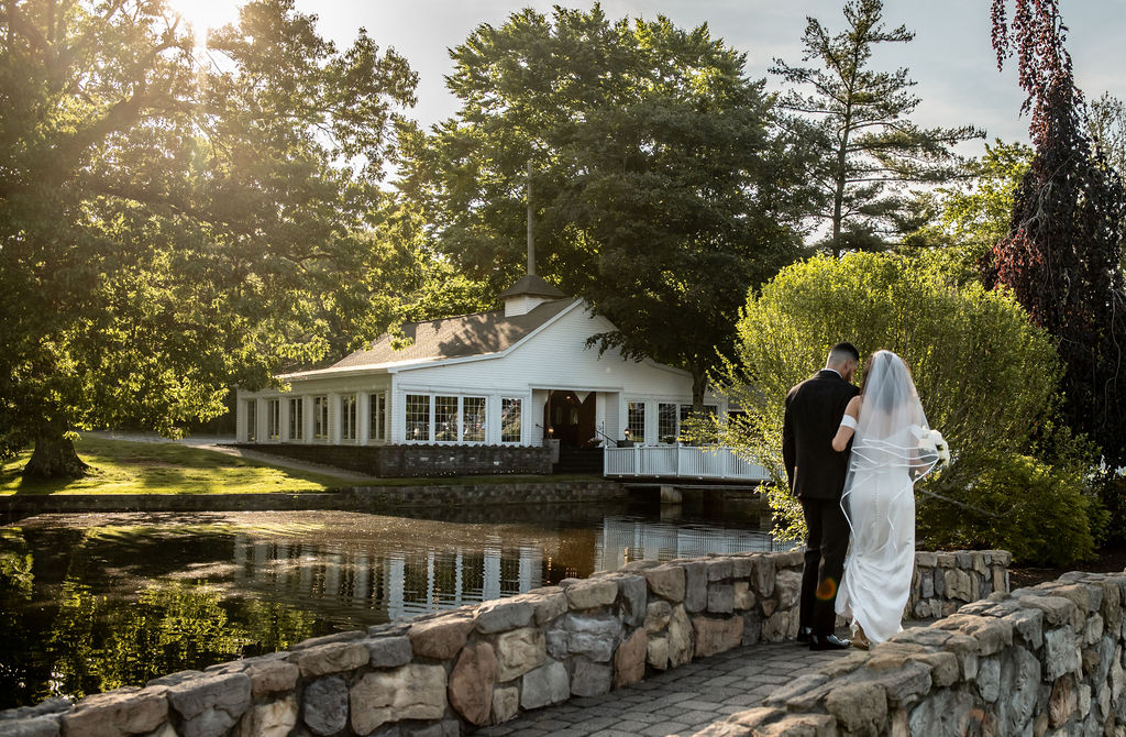 Bride and Groom walking across bridge over water on a beautiful day at the Aqua Turf Club