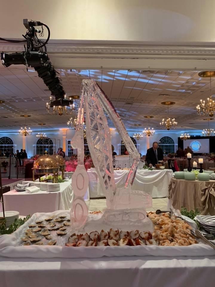 Ice sculpture of industrial crane sits in the middle of a seafood spread