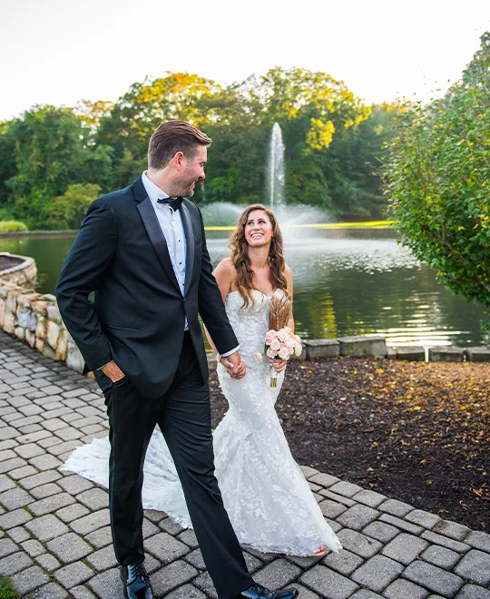 Bride and groom walking outside next to pond