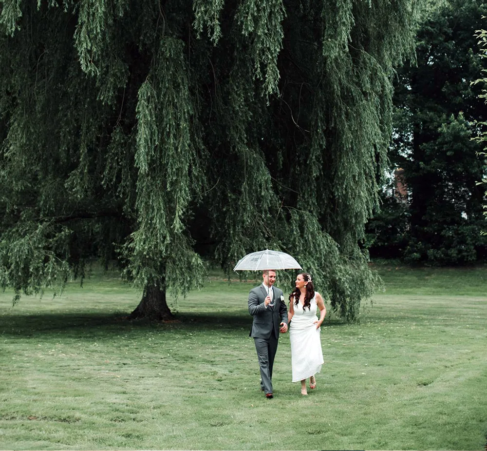 Bride and groom walking outside with umbrella